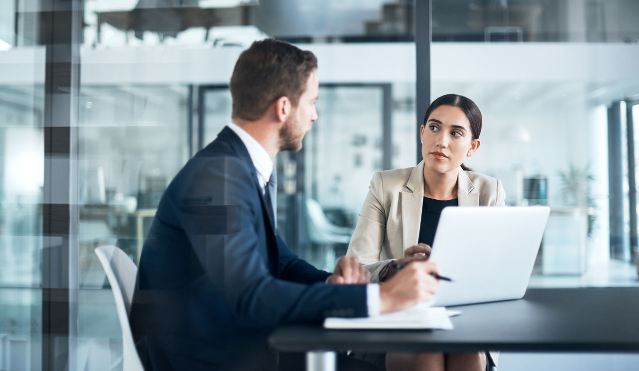 Two businesspeople working on a laptop in the boardroom