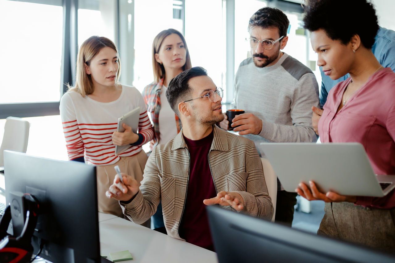 Software developers work in front of desktop computer in office