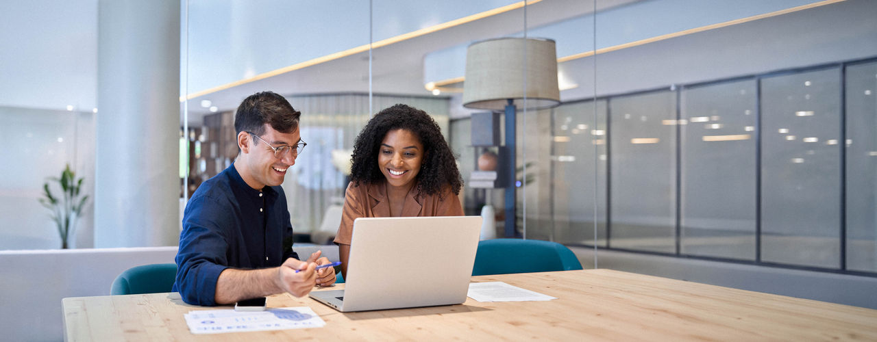 Smiling professionals working together on computer in an office