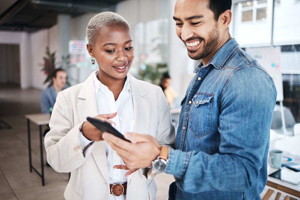 Two sales people looking over tablet discussing business plans