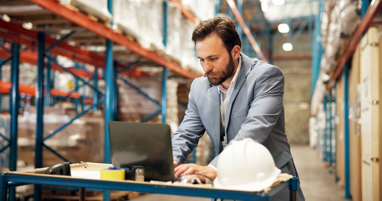 Procurement manager looking at computer in warehouse