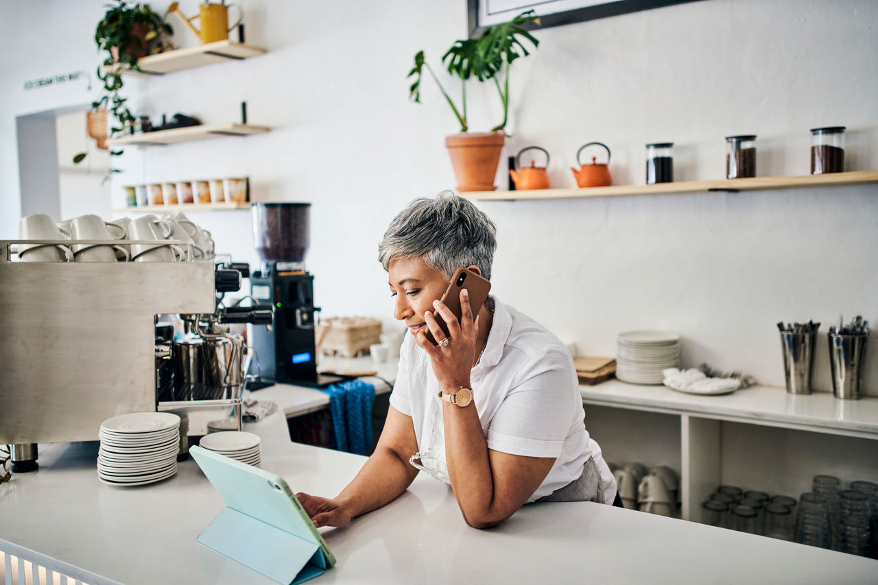 Woman in coffee shop, small business with tablet and phone