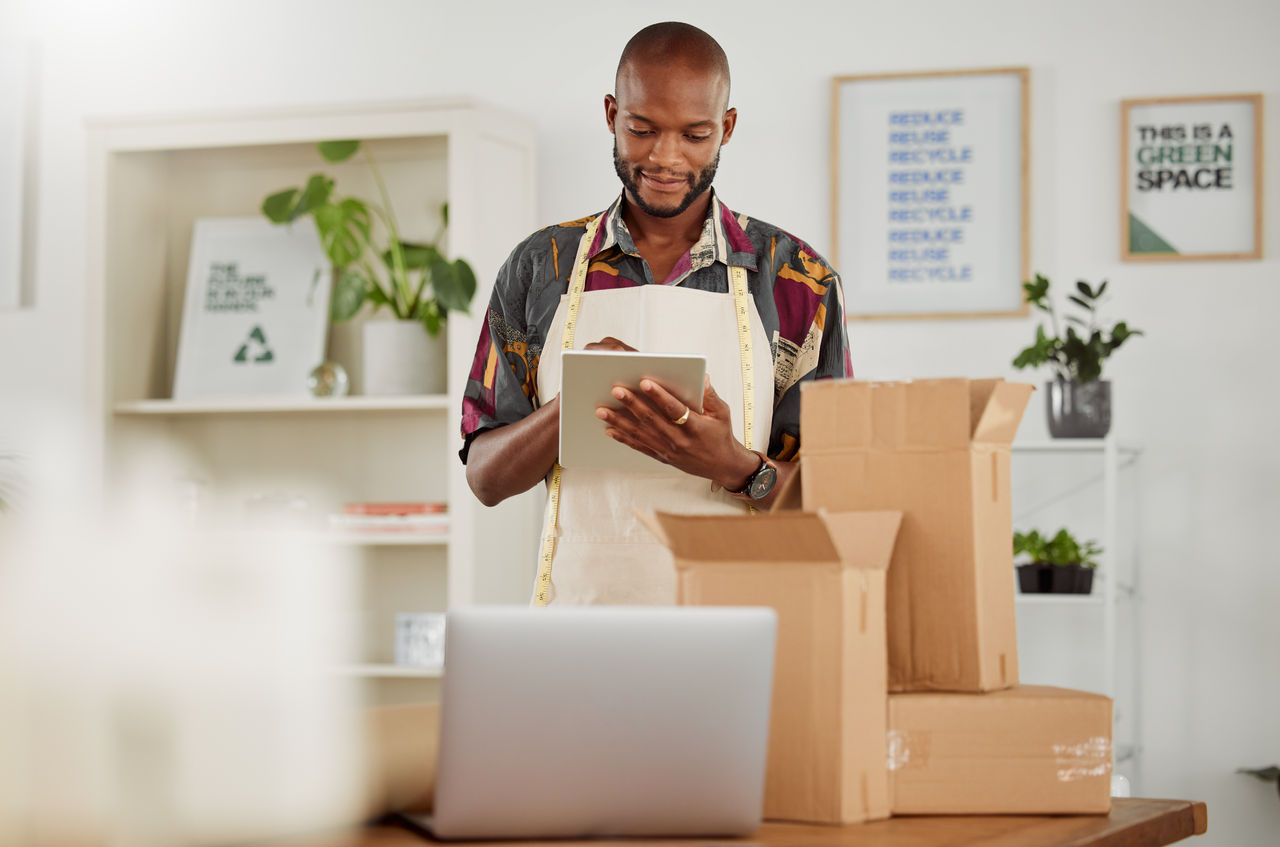 Small business owner or creative startup entrepreneur checking an online order. Fashion, style and design with a trendy designer and tailor working on a tablet in his textile workshop