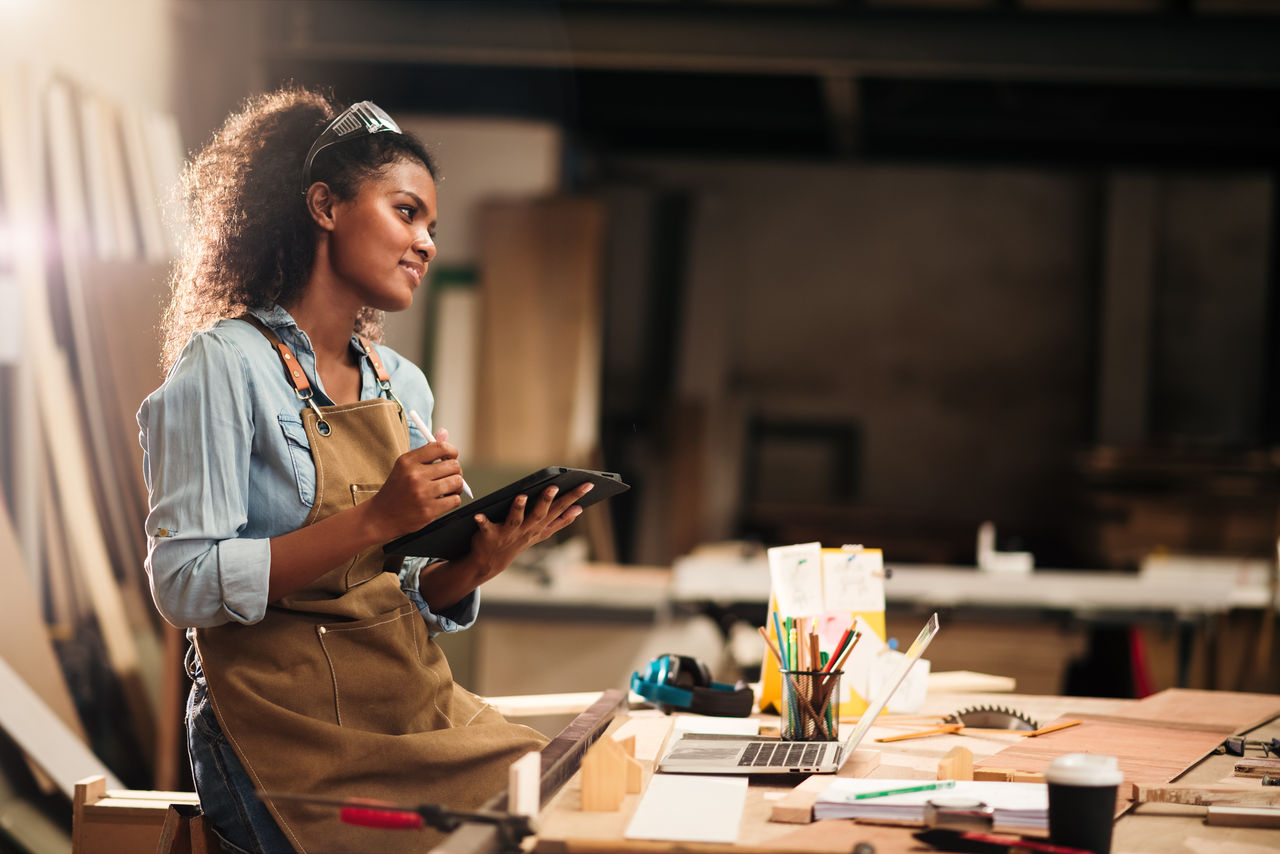 Young attractive african american female carpenter in wood working in small business workshop. Wood  industry and furniture industrial.